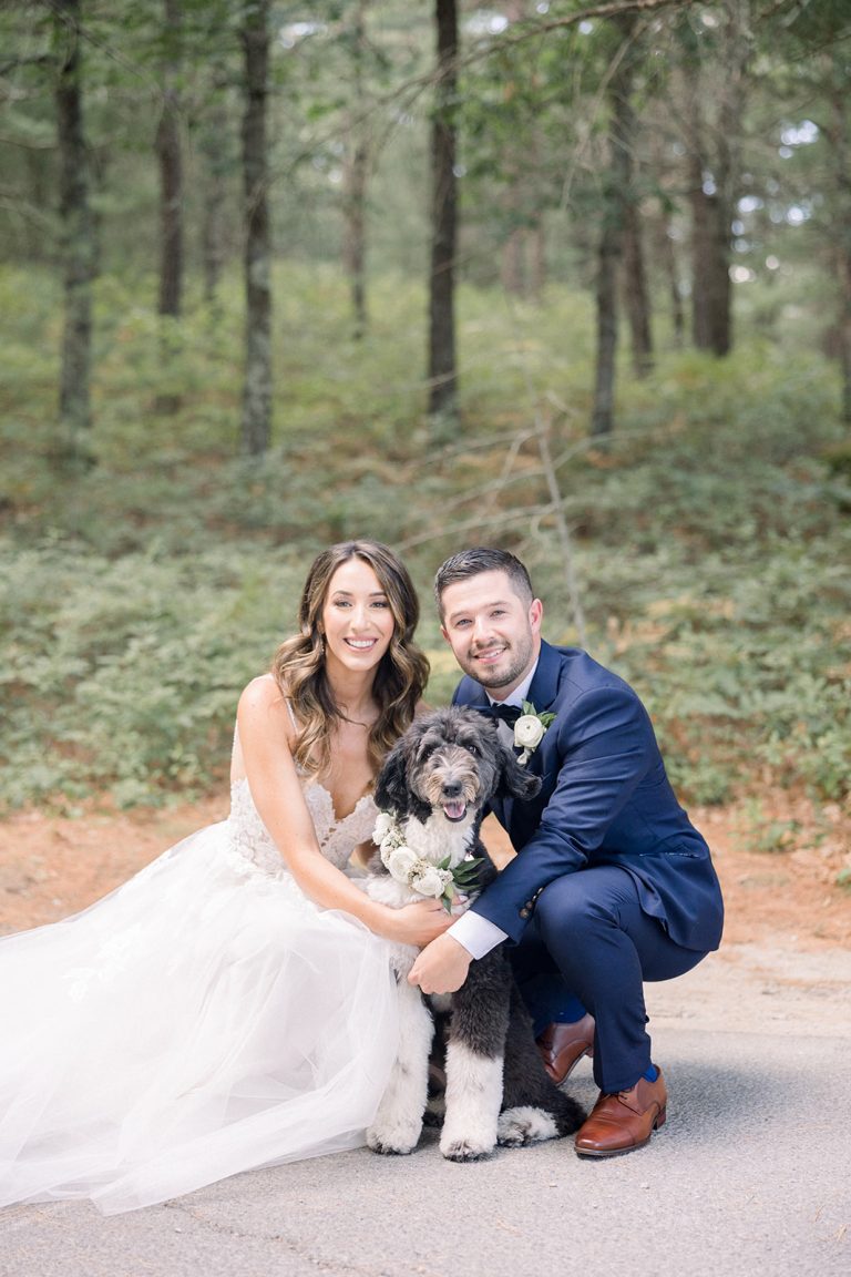 bride and groom pose with dog with floral collar