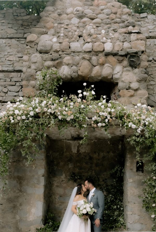 beautiful wedding floral arrangements surrounding bride and groom at outdoor wedding venue