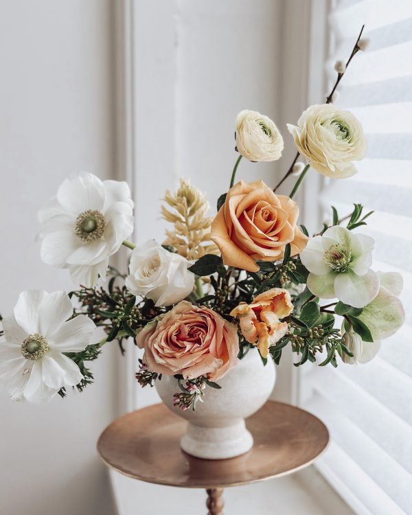 a gorgeous floral arrangement with white, orange, and yellow flowers in a white vase